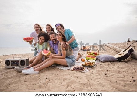 Full length photo of funky ladies guys eat fruits near boombox wear casual cloth outdoors on the beach