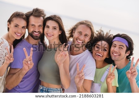 Photo of adorable charming fellows company enjoying good weather showing v-signs outside seaside beach