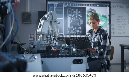 Female Startup Developer Holding Laptop while Working with Robotic Arm. Woman Looking at Screen and Programming Bionic Limb. High-Tech Science and Research in University Lab Concept. Royalty-Free Stock Photo #2188603473