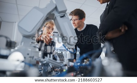 Two Concentrated Students Express their Ideas and Assumptions Standing Around Bionic Robot Arm with Female Teacher at University Class. Computer Science Education Build, Learn Concept. Low Angle View Royalty-Free Stock Photo #2188603527
