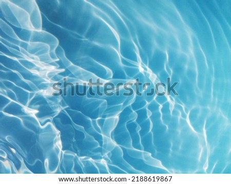 Closeup​ defocus blurred blue watercolor in swimming pool rippled water detail background. Water splash, water spray background. Abstract​ of​ surface​ blue​ water​with​ sunlight​ for​ background.