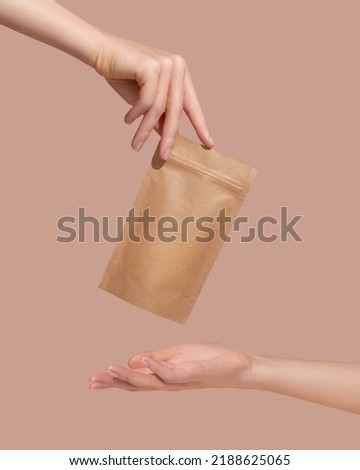 Woman's hands hold cardboard packages for tea or snacks on a beige background. Tea branding and packaging mockup. High quality photo Royalty-Free Stock Photo #2188625065