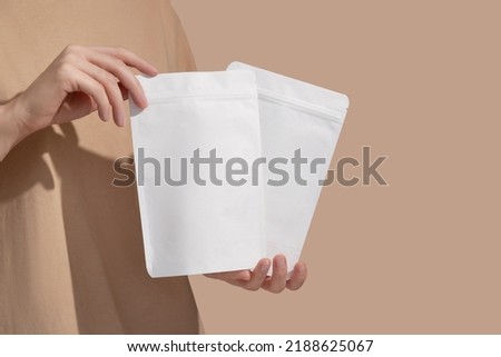 Woman's hands hold cardboard packages for tea or snacks on a beige background. Tea branding and packaging mockup. High quality photo Royalty-Free Stock Photo #2188625067