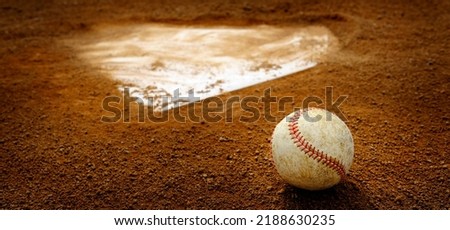 Old leather baseball on dirt field by home plate or a base 