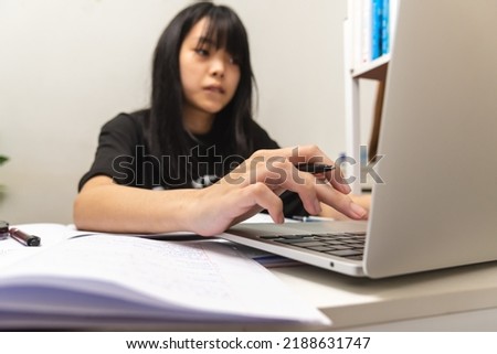 Asian teen girl use computer laptop technology internet online research information social network and education homework on table.