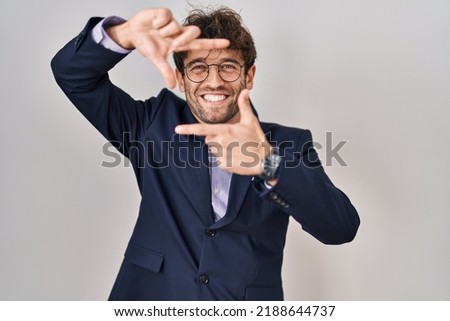 Hispanic business man wearing glasses smiling making frame with hands and fingers with happy face. creativity and photography concept. 