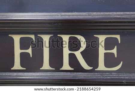 A close up view of a brown and cream painted sign that says fire.