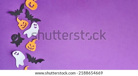 Halloween decorations, pumpkins, candy, on purple background. Halloween party greeting card. Copy space. Flat lay, top view, overhead.