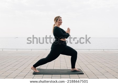plus size girl practicing yoga in front of the ocean on a summer day Royalty-Free Stock Photo #2188667501