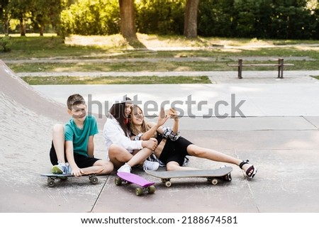 Children with skateboard and penny boards making selfie on phone on the sports playground. Children friendship concept. Kids smile and laugh and have fun together
