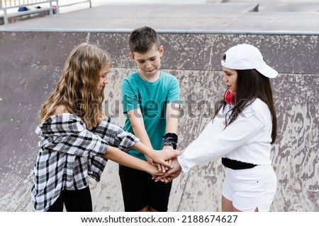 Stack of children hands. Concept of friendship sports support of children. Kids with skateboards and penny boards posing together on sport ramp on skate board playground