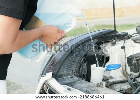 Woman pours windshield cleaning fluid. Flow windshield fluid into the windshield washer reservoir. Water tank wiper on car engine room, Maintenance concept. Royalty-Free Stock Photo #2188686461