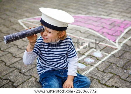 Creative leisure for children: Funny little  preschool child of four years having fun with ship or boat picture drawing with chalk.