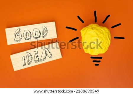 Good Idea, written in youth style on wooden blocks, Beautiful orange background, Crumpled ball of paper in the form of a burning light bulb, Concept, Brainstorming, Innovative ideas,
