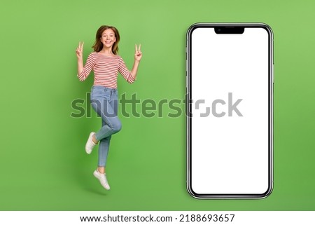 Photo of cheerful friendly lady jump show v-signs wear striped shirt jeans sneakers isolated green color background