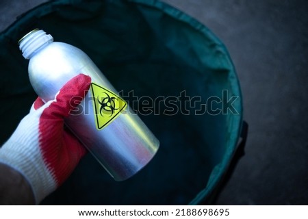 A bottle with a radioactive substance in the trash. Disposal of radioactive waste. Specialized service for the disposal of harmful substances.