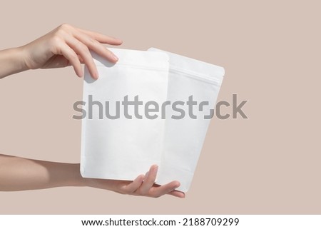 Woman's hands hold cardboard packages for tea or snacks on a beige background. Tea branding and packaging mockup. High quality photo Royalty-Free Stock Photo #2188709299