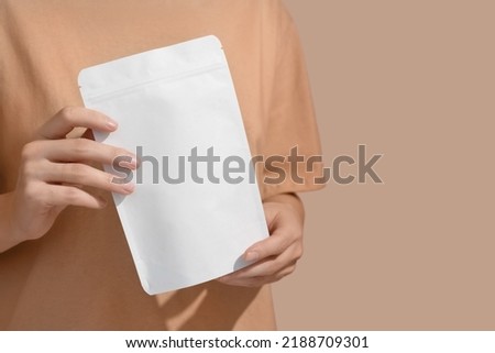 Woman's hands hold cardboard packages for tea or snacks on a beige background. Tea branding and packaging mockup. High quality photo Royalty-Free Stock Photo #2188709301
