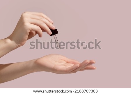 Woman hand holding facial essential oil or serum packaging on pink background. Beauty cosmetic product for skincare concept. Mockup. High quality photo Royalty-Free Stock Photo #2188709303