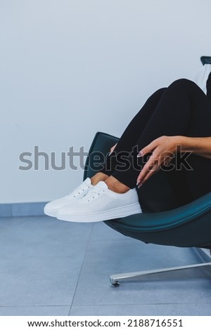 Women's legs close-up in white leather sneakers made from natural leather.Collection of women's summer shoes