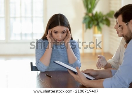 Stressed businesswoman realtor touching temples, dissatisfied clients reading documents, complaining, demanding compensation, arguing with lawyer, manager at meeting, bad contract terms Royalty-Free Stock Photo #2188719407
