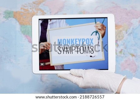 doctor showing tablet PC with monkeypox symptoms screen in the front of map.