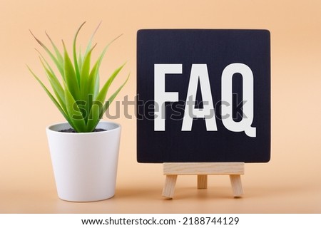 Text FAQ (Frequently Asked Questions) on a chalkboard next to a office plant on a light background. Business concept.