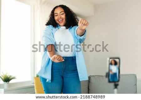 Happy African American Woman Blogger Making Video On Smartphone Having Fun Dancing At Home. Modern Blogging And Gadgets Lifestyle Concept. Selective Focus