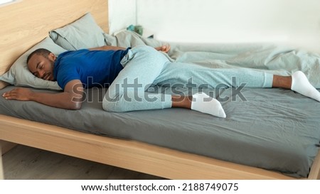 Black Guy Sleeping Lying On Stomach On Bed In Bedroom Indoor. Millennial Man Resting Napping Peacefully At Home. Healthy Sleep, Rest And Relaxation Concept. Panorama