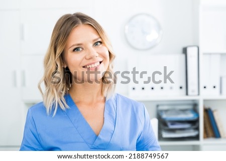 Friendly girl in doctor's uniform smiling at office. High quality photo