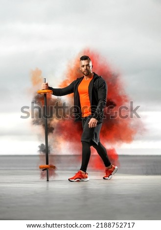 Download the perfect fitness pictures. Bodybuilder athlete in orange sportswear doing barbell exercises in the outdoors gym. Powerful fitness workout.