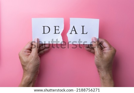 Business deal or transaction concept with the word - Deal - split over two pages of paper on different clipboards with businessmen holding two papers. business concept. Royalty-Free Stock Photo #2188756271