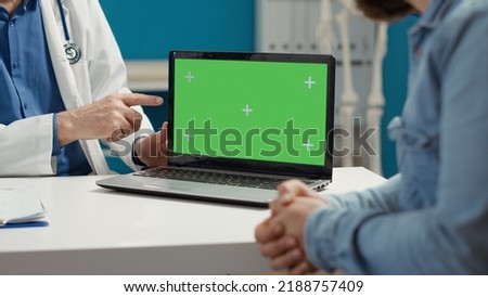 Health physician and sick patient looking at greenscreen on laptop computer in medical cabinet. Blank copyspace template with isolated chroma key and mockup background. Close up.