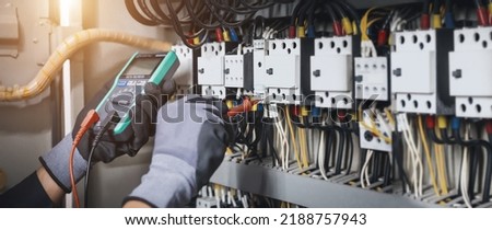 Electricity and electrical maintenance service, Engineer hand holding AC multimeter checking electric current voltage at circuit breaker terminal and cable wiring main power distribution board. Royalty-Free Stock Photo #2188757943