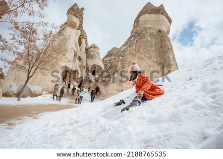 happy little girl in red sliding on a pile of snow in pasabag valley cappadocia