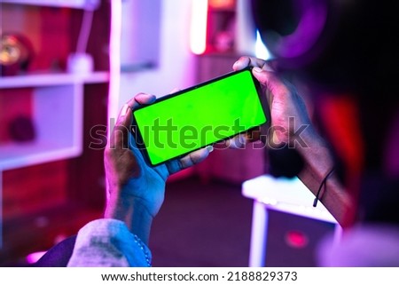 Close up shot of gamer playing video game on green screen mobile phone at home - concept of entertainment, promotion and technology