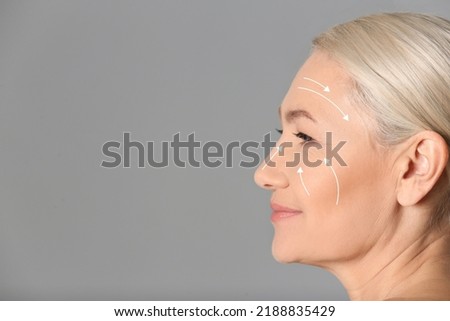 Beautiful mature woman after facelift cosmetic surgery procedure on grey background. Space for text Royalty-Free Stock Photo #2188835429