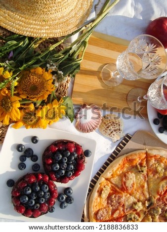 Summer picnic on the beach. food and drink concept. two glasses, wooden tray, Italian pizza, cheese, fruit and a straw hat