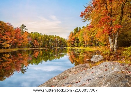 Beautiful autumn foliage reflected in still lake water in New England Royalty-Free Stock Photo #2188839987
