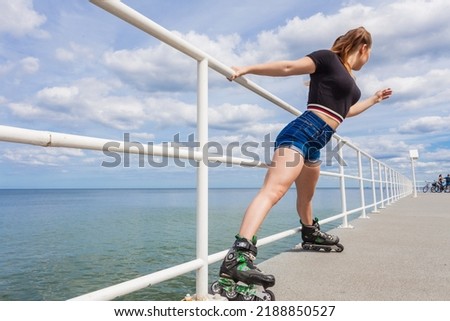 Happy joyful young woman wearing roller skates on sea. Girl having fun during summer time.