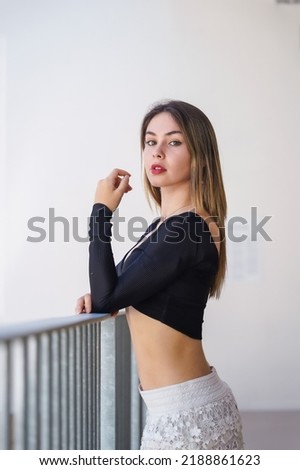 A woman on the railing of a white building, fashion portrait of a gorgeous young woman
