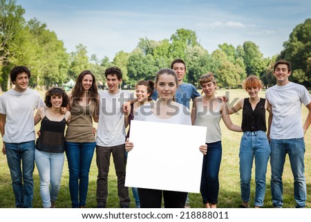 Group of friends at the park on a summer day. A girl holds hands with a white copy space.