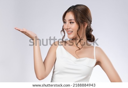 Photo of a gorgeous woman with flawless healthy fresh skin in a concept of empty space for beauty care product. Skincare product, model uses hand to create empty space for commercial.