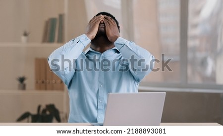 Frustrated shocked african businessman american adult man student work on computer make error mistake feels stress upset with bad news failure e-commerce exam lost internet connection lose online Royalty-Free Stock Photo #2188893081