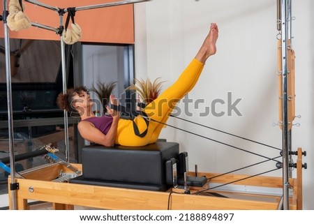 Woman doing pilates moves with reformer in studio