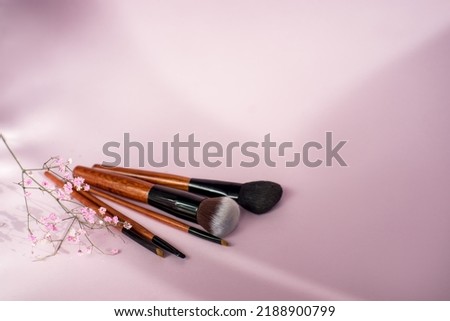 eye makeup brushes lie near a palette of eyeshadows on a pink background. High quality photo