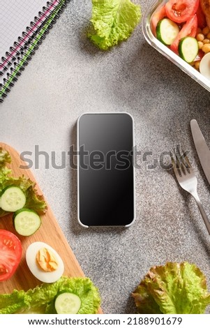Weight loss concept, calories counting, diet, food control and Calorie counter application on smartphone with salad, egg and vegetable. Top view. Copy space. Vertical .