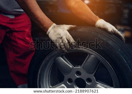 Mechanic holding a tire at the repair garage. Repair service.