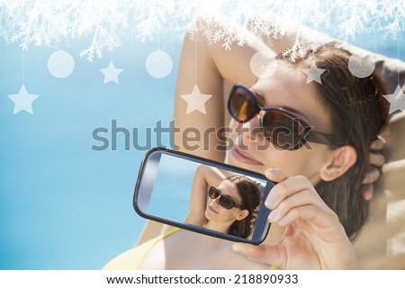 Hand holding smartphone showing photo against fir tree forest and snowflakes