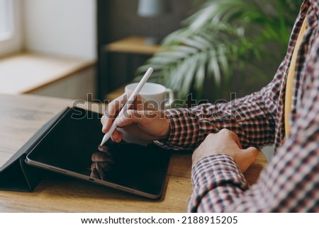 Cropped close up man he wearing shirt graphic designer hold work use write draw stylus pc pen sit alone at table in coffee shop cafe relax rest in free time. Freelance mobile office business concept